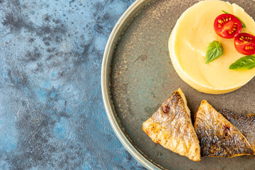 Sea fish fillet fried and a side dish of mashed potatoes close-up in a plate on the table. Restaurant service.