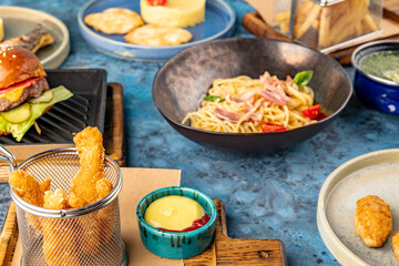 Chicken strips with sauce on the background of a burger, spaghetti and mashed potatoes. Set of food of the children's menu. Dinner.