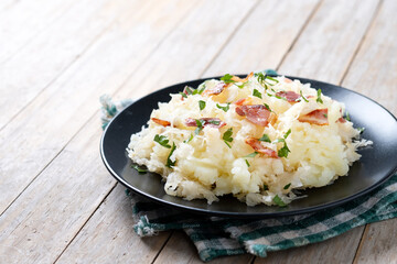 Slovak potato dumplings halusky with steamed sauerkraut and bacon on wooden table. Copy space