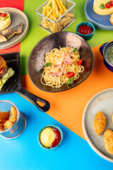 Top view of spaghetti with bacon, french fries with ketchup, mashed potatoes with tomato. Vertical photo. Set of food of the children's menu. Dinner.