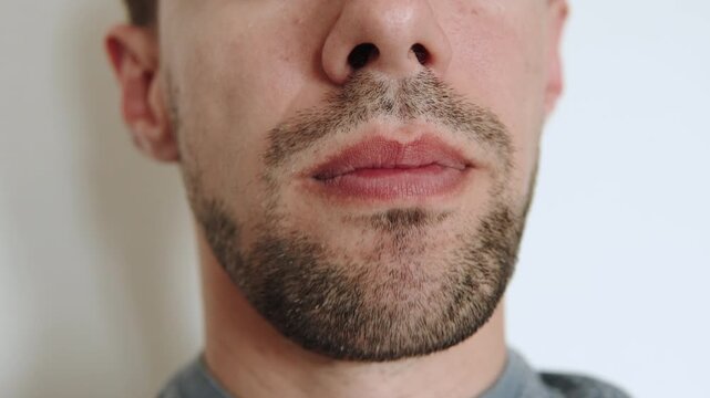 Chewing mouth of caucasian man close up. Grinding of food and movement of lower jaw and chin. Person with stubble on his face.