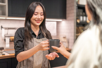 Portrait of asian barista woman small business owner working behind the counter bar and receive order from customer on coffee packaging and cup of coffee background in cafe or coffee shop