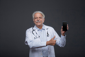 Male Surgeon Holding Phone In One Hand And Making Thumbs Up Sign Through Another Hand