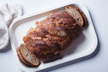 Sliced ​​rye bread with caraway seeds on white tray.