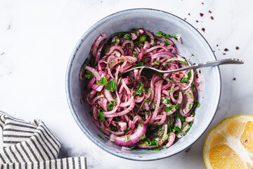 Turkish sumac onion salad in gray bowl, white background.