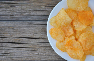 potato chips in a white bowl.  potato chips on a plate on a wooden table top view. selective focus