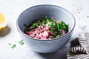 Turkish sumac onion salad in gray bowl, white background.