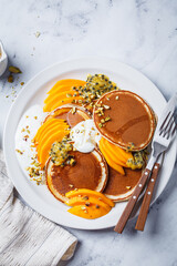 Breakfast pancakes with mango and passion fruit on white plate. Healthy vegan recipe.