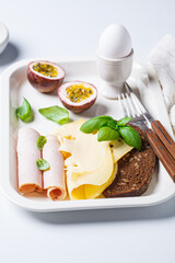 Ham, cheese, bread and boiled egg breakfast plate, white background.