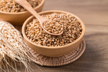 Whole wheat grain in wooden bowl with spoon, Food ingredient