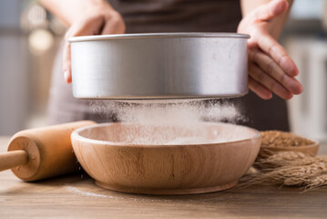 Sifting flour through sieve into wooden bowl, Food ingredient prepare for cooking or baking