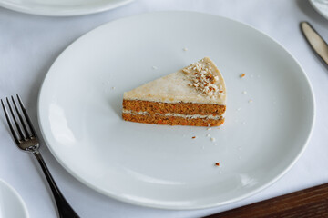 delicious cake with white buttercream, white sponge layers, and fresh nuts, served on a beautiful white plate on a wooden table in a cozy, charming restaurant