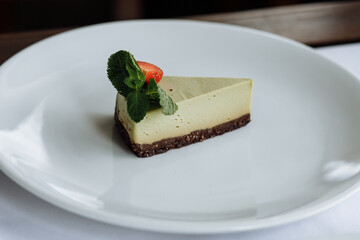 delicious cake with green cream, topped with fresh, fragrant strawberries and layered with black cake, is served on a beautiful white plate in a cozy, charming café