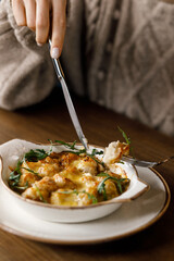 cute girl is enjoying a delicious dish with crispy potatoes, fresh vegetables, fragrant herbs, and creamy cheese on a beautiful black plate in a cozy, charming café.