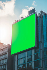 Obraz premium Large green digital billboard on modern building against a bright sky during the day