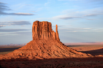 Beautiful view of the iconic West Mitten Butte in Monument Valley, Arizona, illuminated by the warm glow of a stunning sunset. A landscape showcasing the unique geological formations of the Southwest.