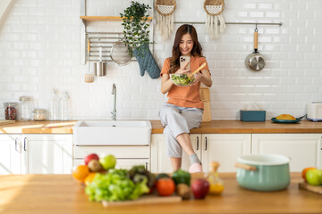 Portrait of beauty body slim healthy asian woman eating vegan food healthy with fresh vegetable salad in kitchen at home.diet, vegetarian, fruit, wellness, health, green food.Fitness and healthy food