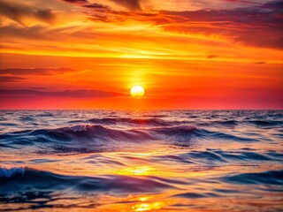 Obraz premium Vibrant orange and pink hues illuminate the serene ocean horizon as the sun dips below the waves, casting a warm golden glow over the calm sea.