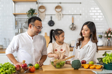 Portrait of enjoy happy love asian family father and mother with little asian girl daughter child help cooking food healthy eat together with fresh vegetable salad and sandwich ingredient in kitchen