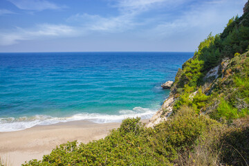 Seascape. Green slope coast and sandy beach. Bright spring day.