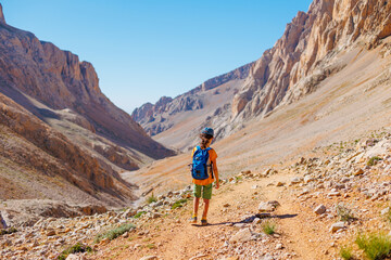 Fototapeta premium summer camp. boy with a backpack. child travels in the mountains with a backpack. summer hike in the high mountains.