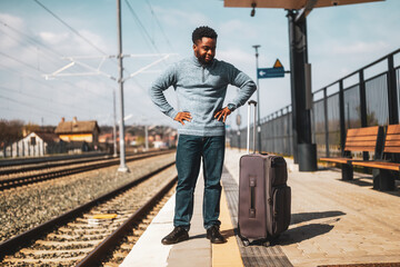 Angry man with a suitcase standing on a railway station.