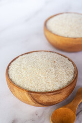 spyllium husk in wooden bowl on white marble table background.