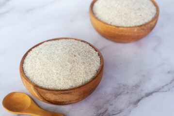 spyllium husk in wooden bowl on white marble table background.