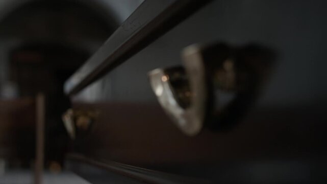 Close up rack focus shot of two metal handles on wall of coffin transported to cathedral for performing funeral service