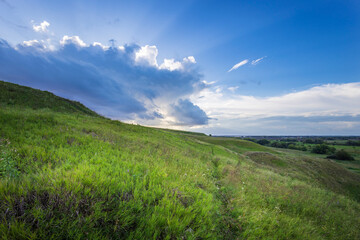 Golden sunlight bathes the lush hills as clouds gather, creating a breathtaking view at dusk, inviting exploration and reflection in nature's splendor.