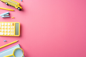 Yellow and blue school supplies arranged on a pink background, including a calculator, pencil, and...