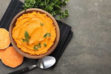 Delicious mashed sweet potatoes with parsley served on gray textured table, flat lay. Space for text