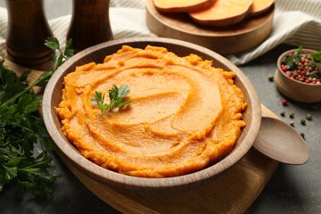 Delicious mashed sweet potatoes in bowl and spices on gray textured table, closeup
