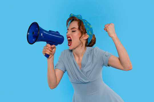Woman in Blue Dress Passionately Shouting Into Megaphone Against Blue Background