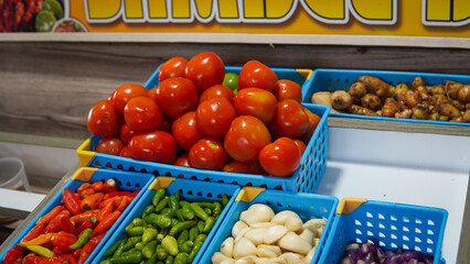 Red peppers, green peppers, garlic, onions, ginger, wooden shelf, blue bins.