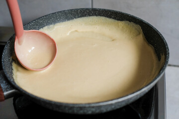 Close up of woman cooking in kitchen at home and frying pancakes on modern stove, preparing pancakes