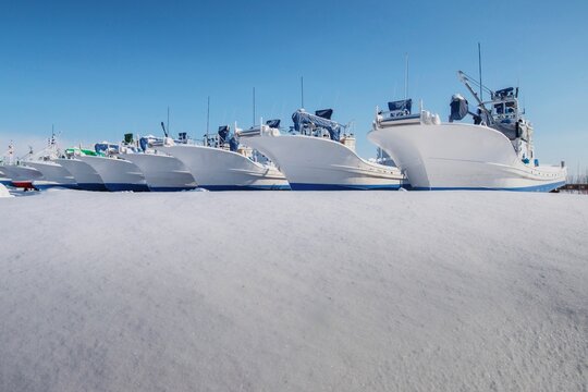 Row of white boats moored in a dry dock in the snow, Hokkaido, Japan