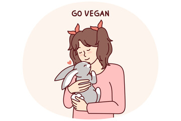 Little vegan older girl hugs rabbit that they wanted to use for food and cook for dinner. Concept of transition to healthy nutrition and promotion of vegan lifestyle from childhood and adolescence