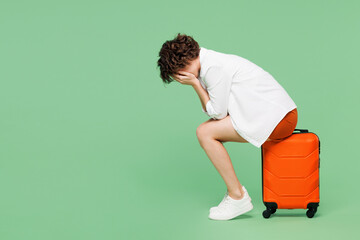 Full body traveler woman wear casual clothes hold sit near suitcase bag cover face with hands cry...