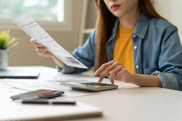 Young Asian woman looking at credit card invoice in her hands and worry about cash on bills payday