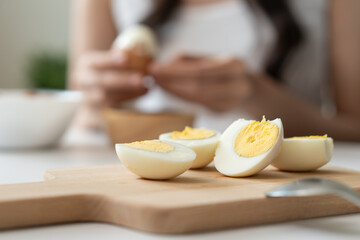 Egg boiled on wooden tray and woman peel egg boil on background.