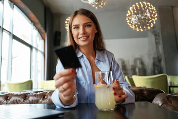 Giving the credit card. Young beautiful woman is in the restaurant