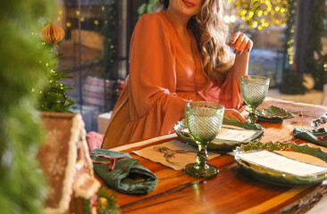 Happy pregnant woman in a pink dress sitting at the festive table. Holiday atmosphere. New Year.