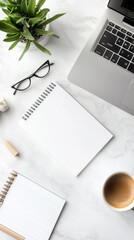 Top view of a office desk featuring a blank notebook, computer, supplies, and a coffee cup