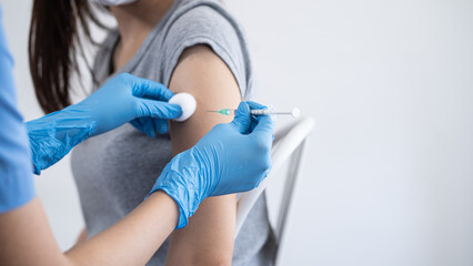 Hand of young woman nurse, doctor giving syringe vaccine, inject shot to Asian arm's patient. Vaccination, immunization or disease prevention against flu or virus pandemic concept