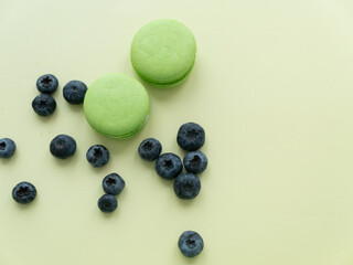 Colorful macaroons. Small sweet tasty French pastries with blueberries on a light background