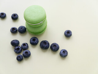 Colorful macaroons. Small sweet tasty French pastries with blueberries on a light background
