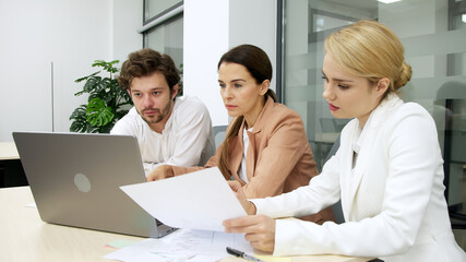 Obraz premium Colleagues in a modern office consult each other, planning project details and financial strategies. Ideal for teamwork, project management, and business planning themes.