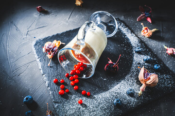 Original serving of the dessert panna cotta with lingonberries, blueberries in a glass lying on a...