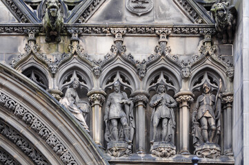 Intricate stone sculptures in a medieval architectural facade, showcasing detailed carvings of historical figures and gothic art.